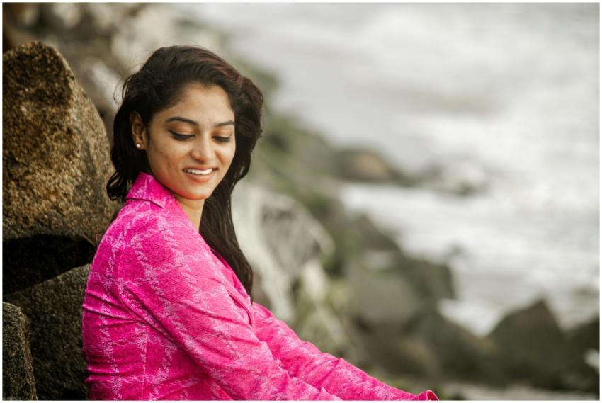 Portrait of a young woman smiling near a rocky bea