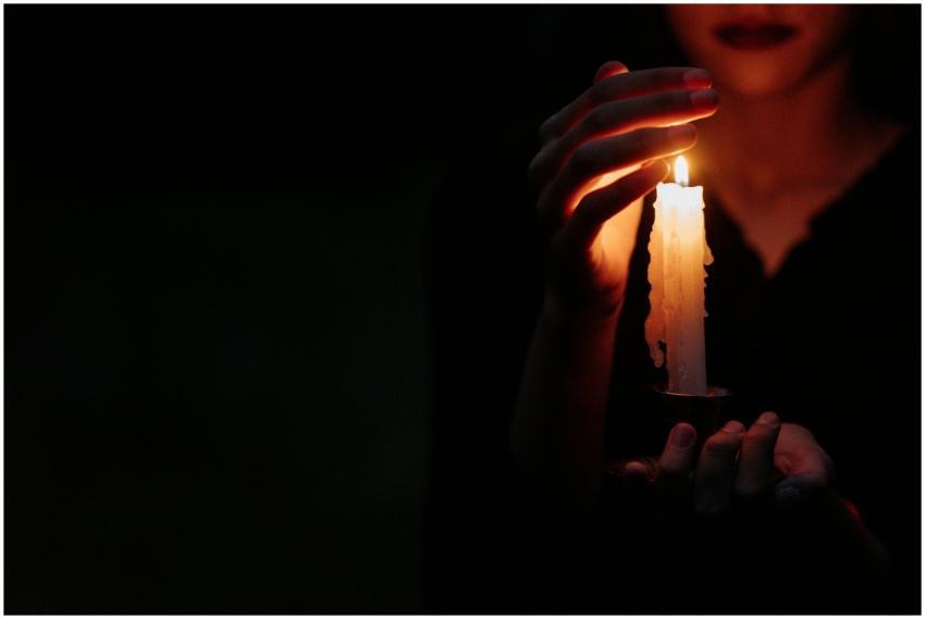 Close-up of a person in the dark holding a single