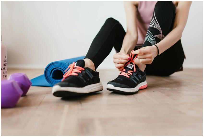 Fit woman tying shoelaces, preparing for indoor wo