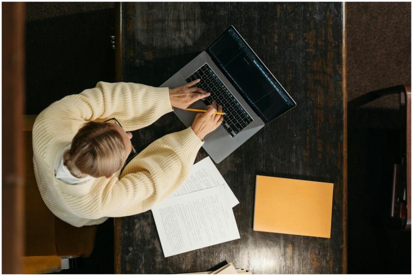Person in a cozy sweater working on a laptop with