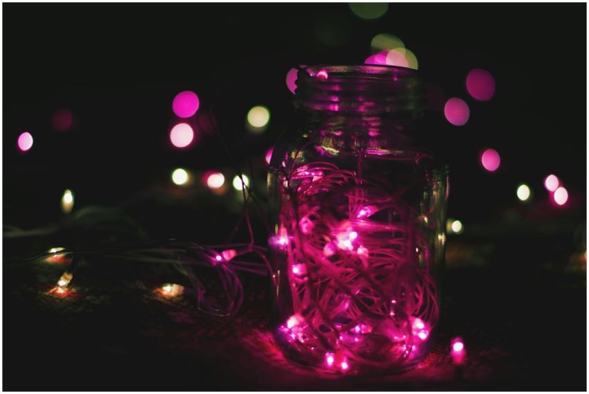 A mason jar filled with glowing pink neon string l