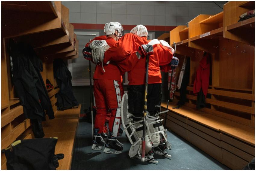 Ice hockey players in red uniforms huddle in a loc