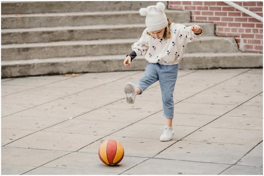Full body of focused little girl in jeans white ju