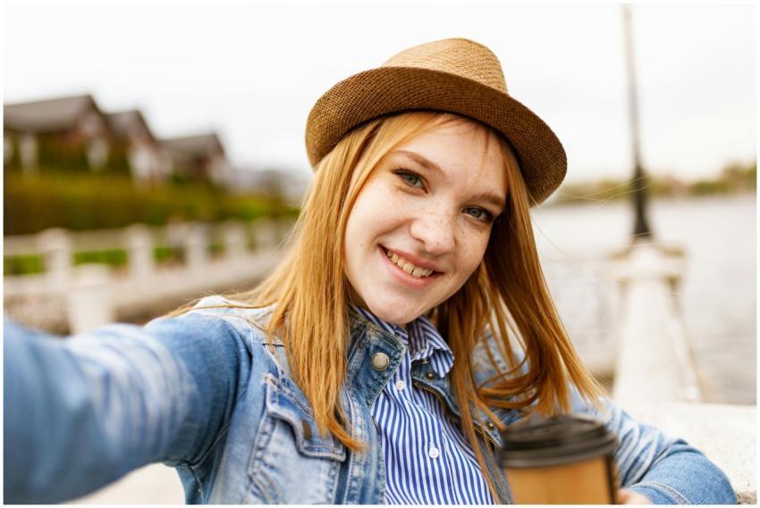 Young woman in a fedora hat takes a selfie with a