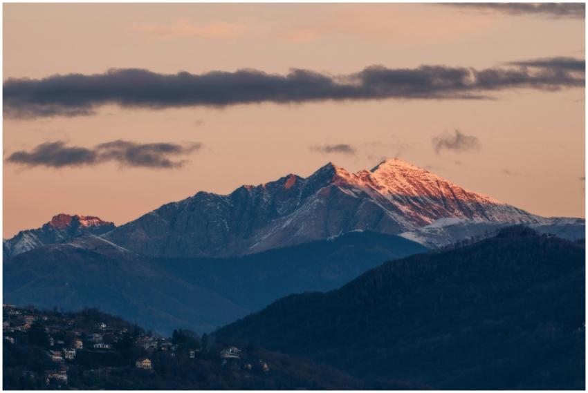 Snowy mountain peaks glow in the dawn light with a