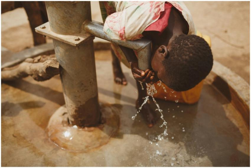 A girl bends to drink clean water from a well in K