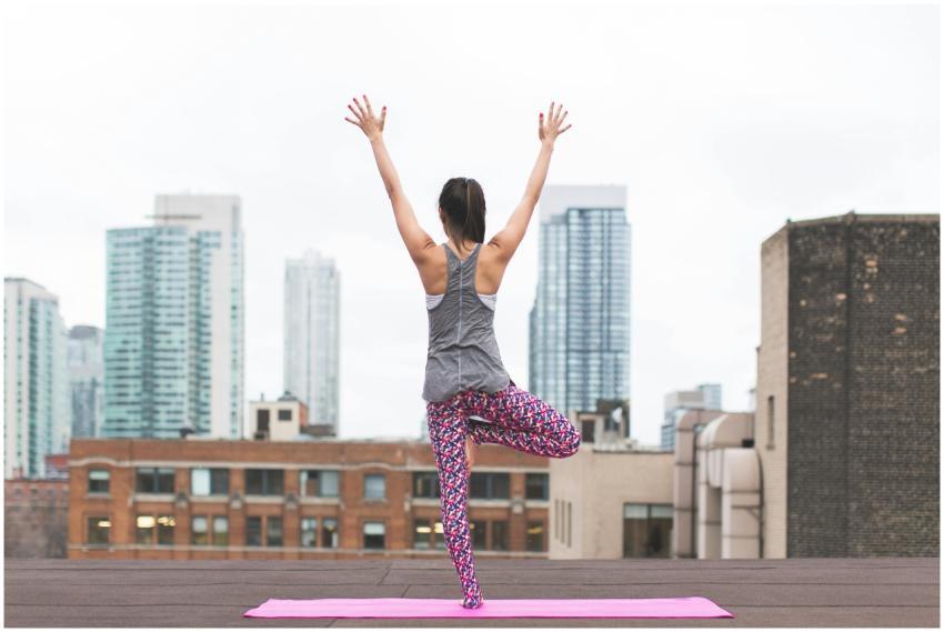 Woman in yoga pose on rooftop with city skyscraper