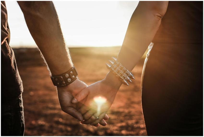 Close-up of a couple holding hands at sunset with
