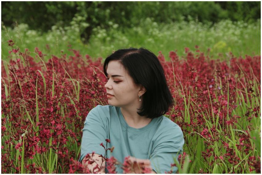 A serene scene of a woman sitting amidst a lush fi