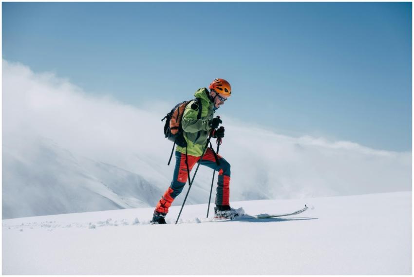 Ski mountaineer exploring snowy mountains under cl
