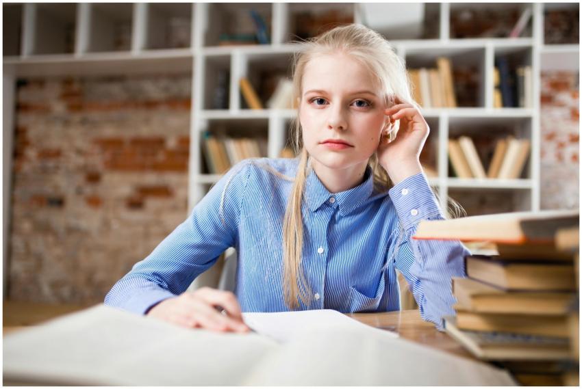 A young woman with blond hair studying at a table