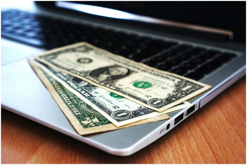 Close-up of US dollar bills placed on a laptop sym