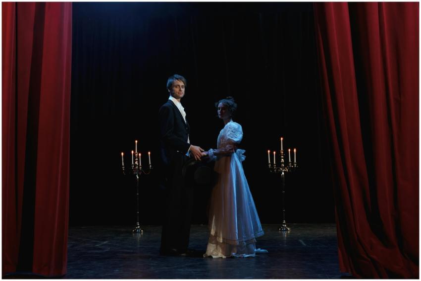 A dramatic theater scene featuring two elegantly d