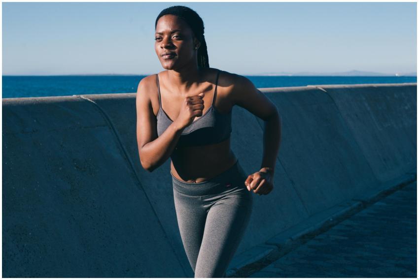 Healthy woman jogging along the oceanfront on a su