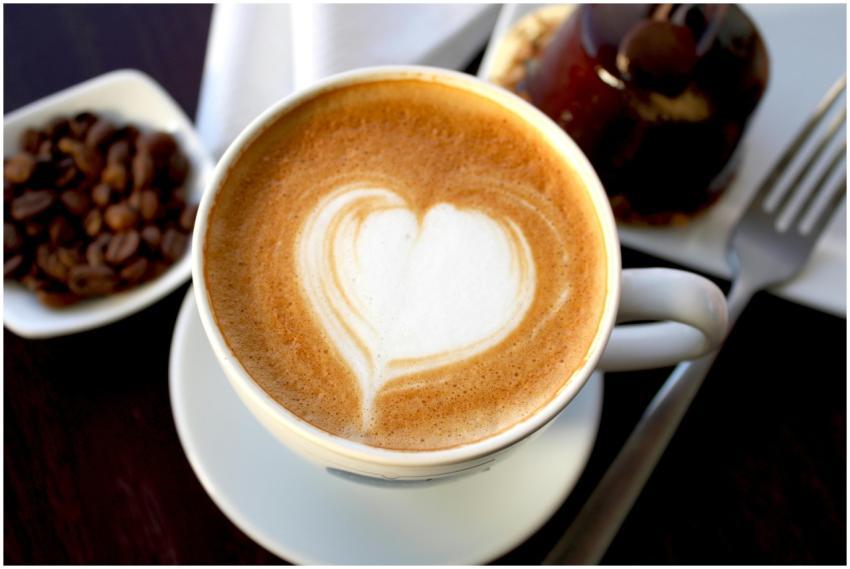 Creamy latte with heart art, surrounded by coffee