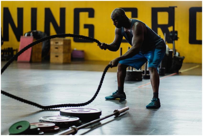 Adult man exercising with battle ropes in a gym ag