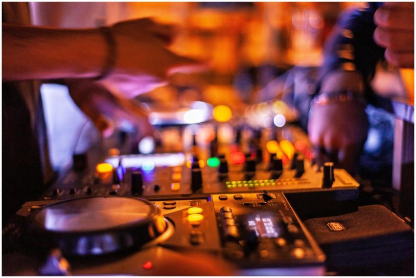 Close-up of DJ mixing console with hands adjusting