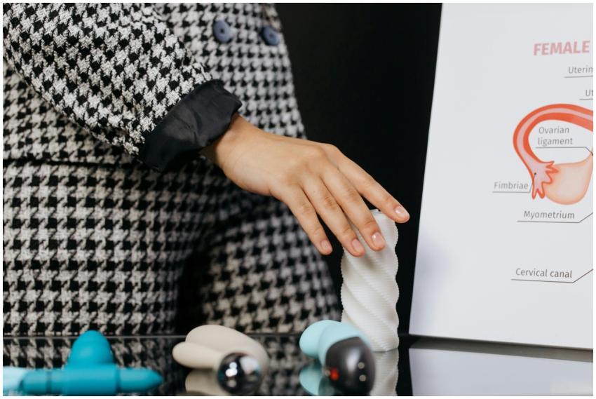 A woman demonstrates with sex toys beside a female