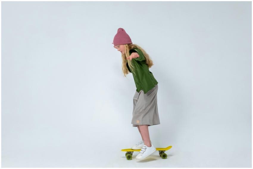 Young girl practicing skateboarding indoors, weari