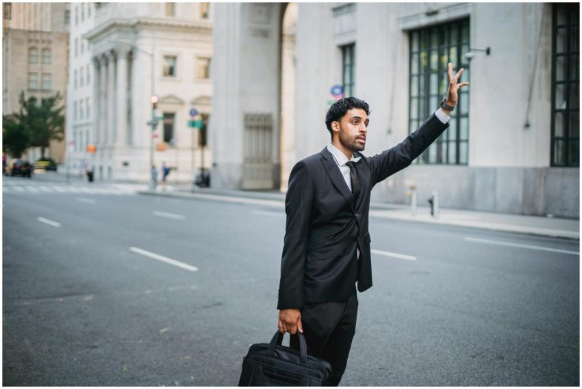 Businessman in formal attire hailing a taxi on a c