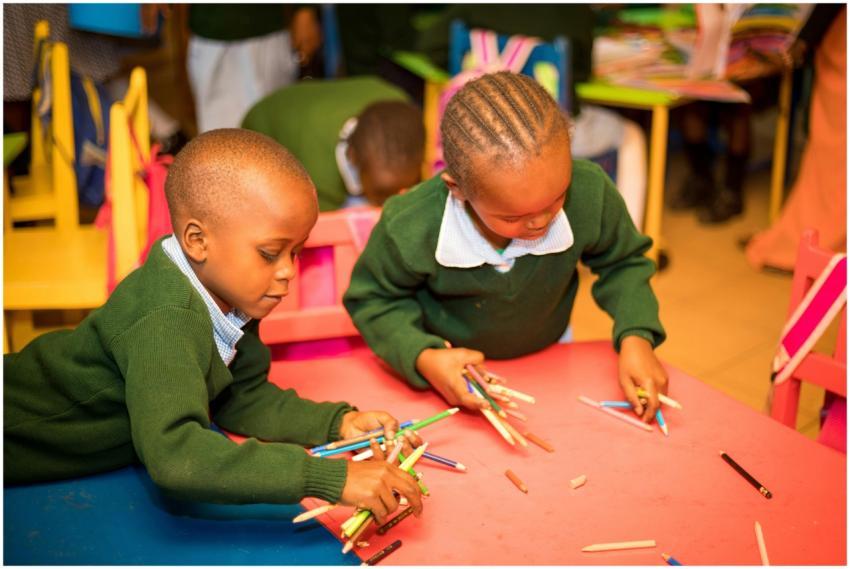 Two children at a table in a classroom, engaged in