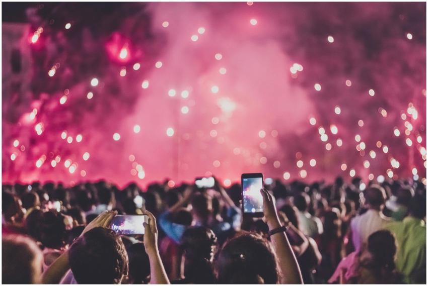 Crowd capturing live fireworks at night festival,