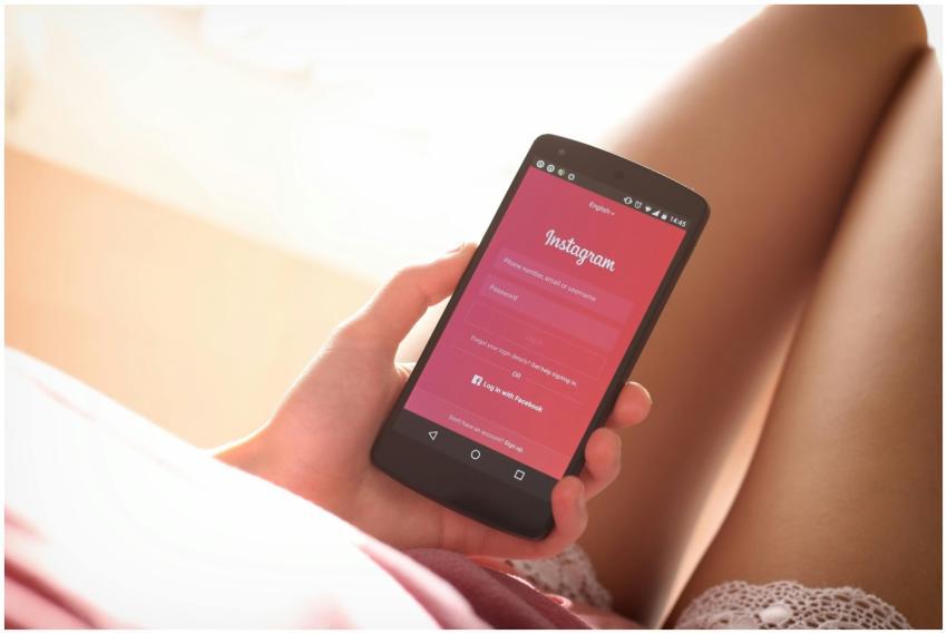 Woman holding a smartphone with Instagram login sc