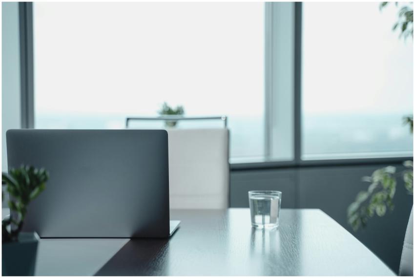 Minimalist office desk featuring a laptop and wate