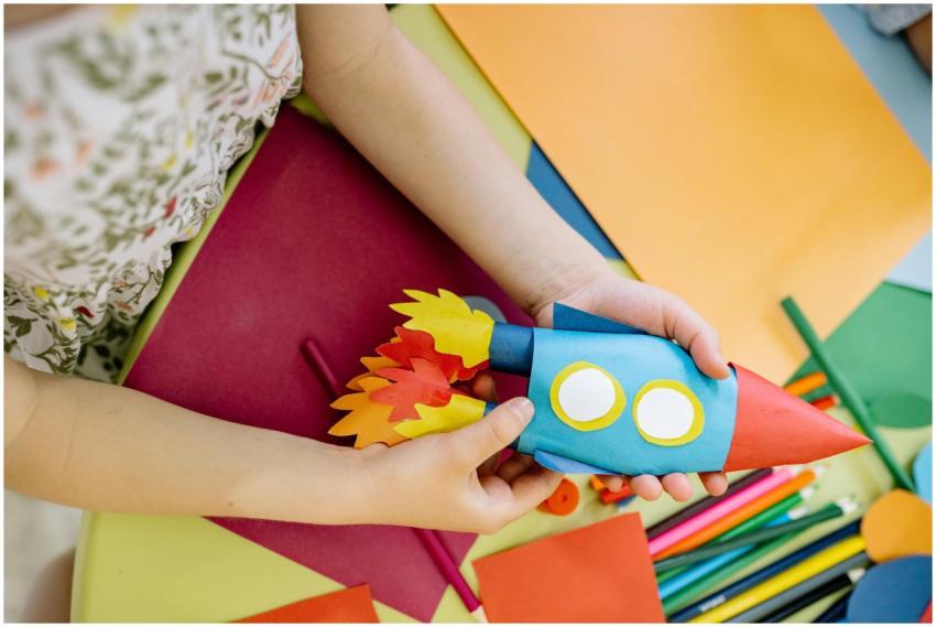 A child builds a vibrant paper rocket during an ar