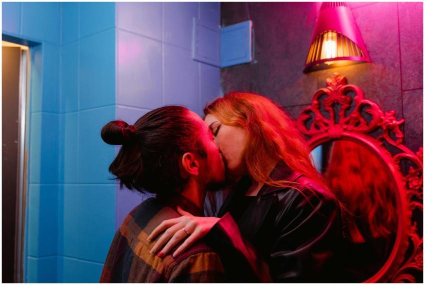 A couple shares a passionate kiss in a vibrant nig