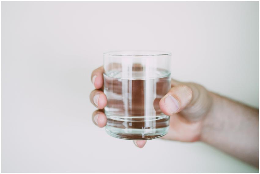 A close-up shot of a hand holding a clear glass of