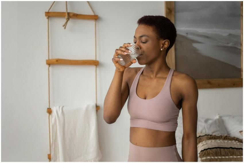 African American woman in sports bra drinking wate
