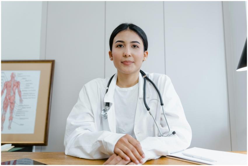 A female doctor confidently sits at her desk, read