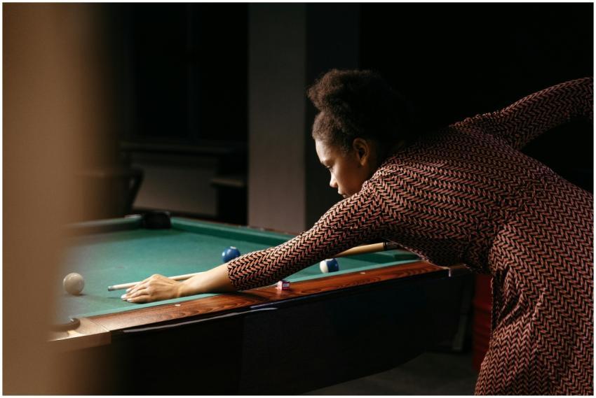 An adult woman skillfully lining up a shot on a bi