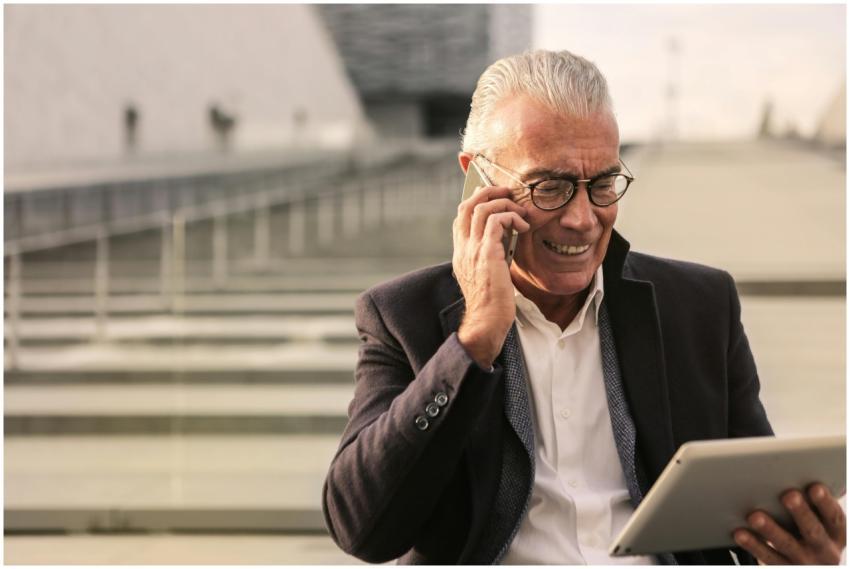 Elderly man in business attire using smartphone an