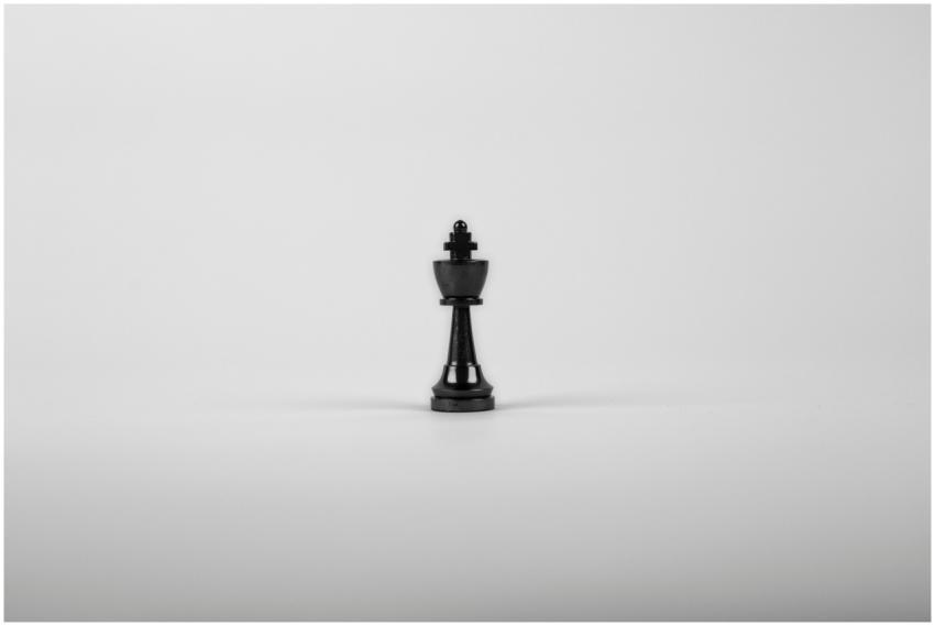 A minimalist black chess king piece on a white bac