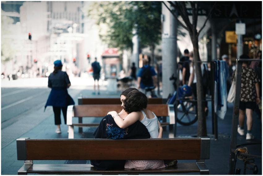 A couple shares an affectionate embrace on a bench