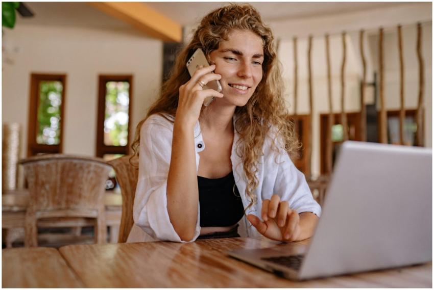 Smiling woman working remotely with a laptop and p