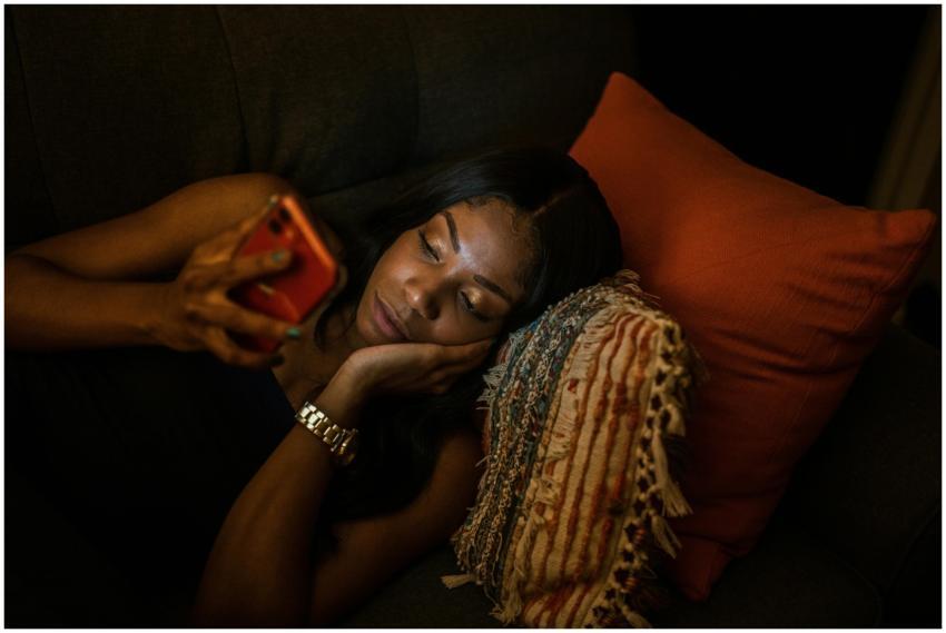 A woman comfortably lying on the couch browsing he