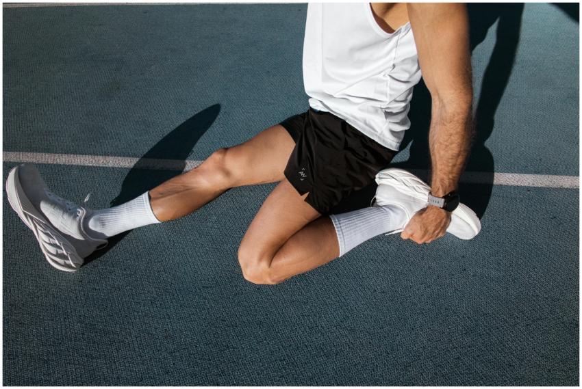 Male athlete stretching on an outdoor track, weari