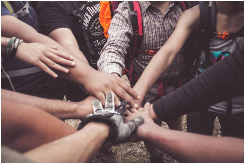 A group of diverse individuals join hands for team