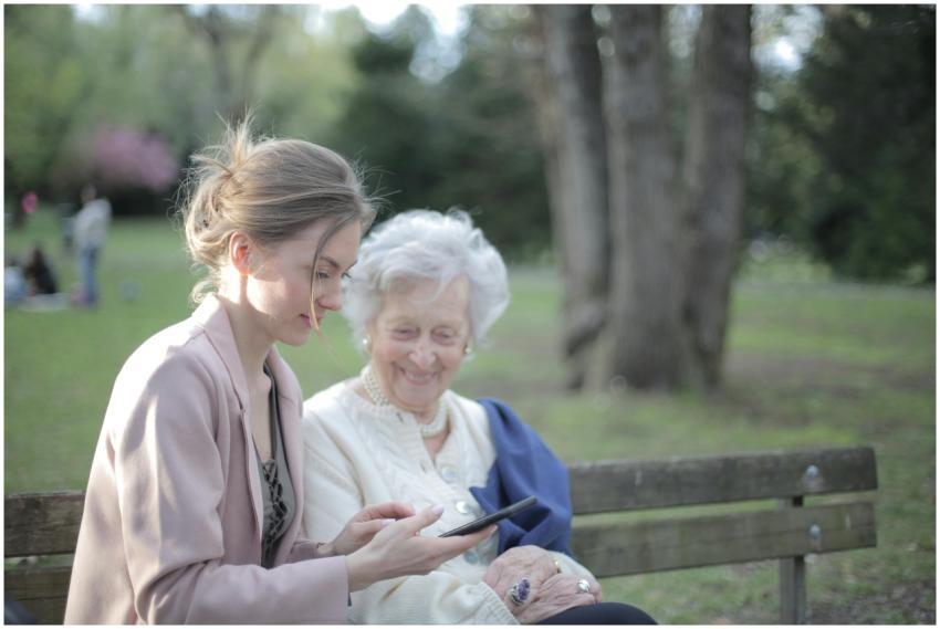 Side view of smiling adult female helping aged mom
