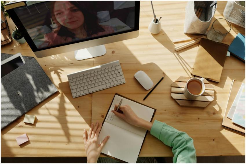 A student taking notes during a video call for onl
