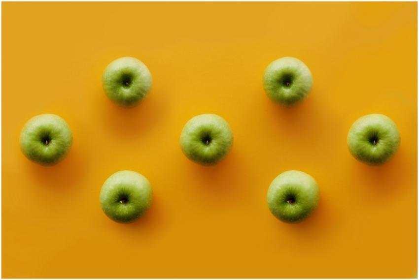 Green apples displayed on a vibrant orange surface