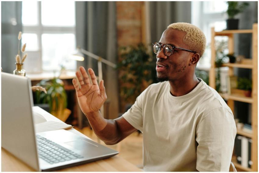 Smiling man in glasses waves during a video call a