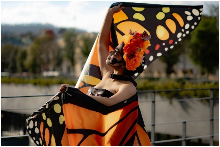 Woman in butterfly-themed costume and makeup poses