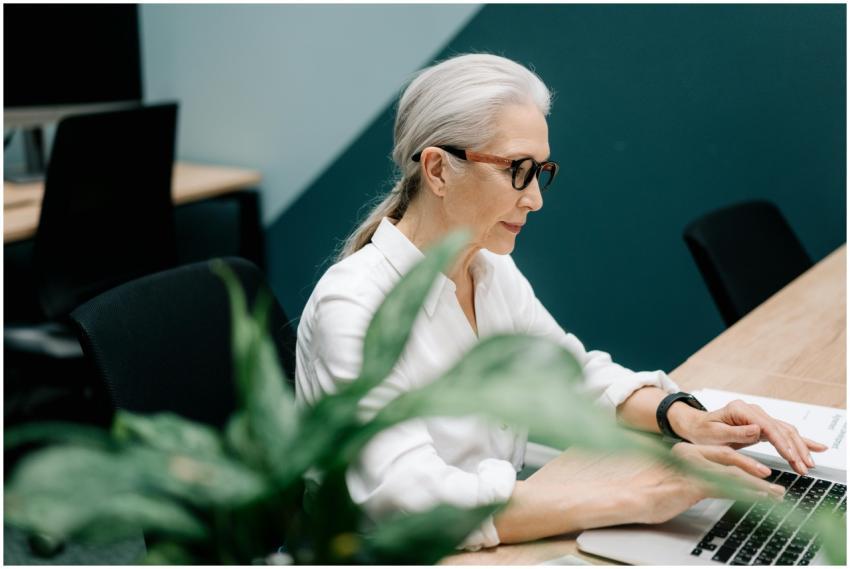Confident senior woman with glasses working on a l