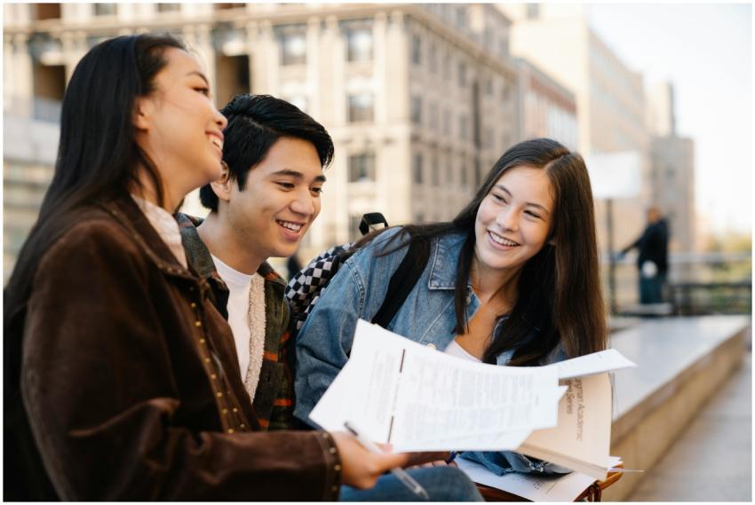 Three young adults sitting on campus benches, enjo