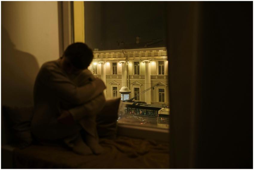 A pensive person sitting by the window at night ov