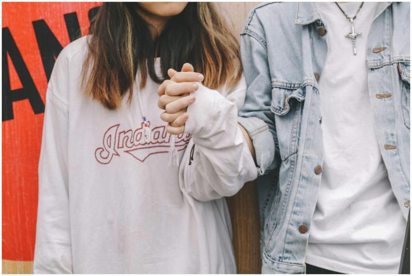 Young couple holding hands in casual attire, symbo